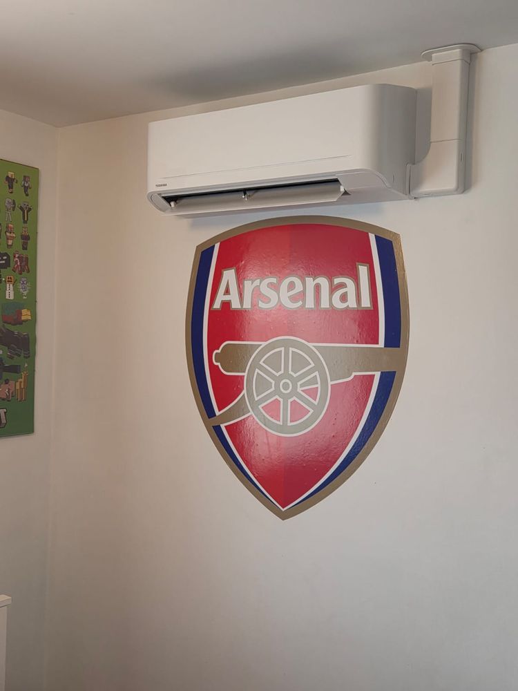 Indoor unit above a painted Arsenal crest in a hallway